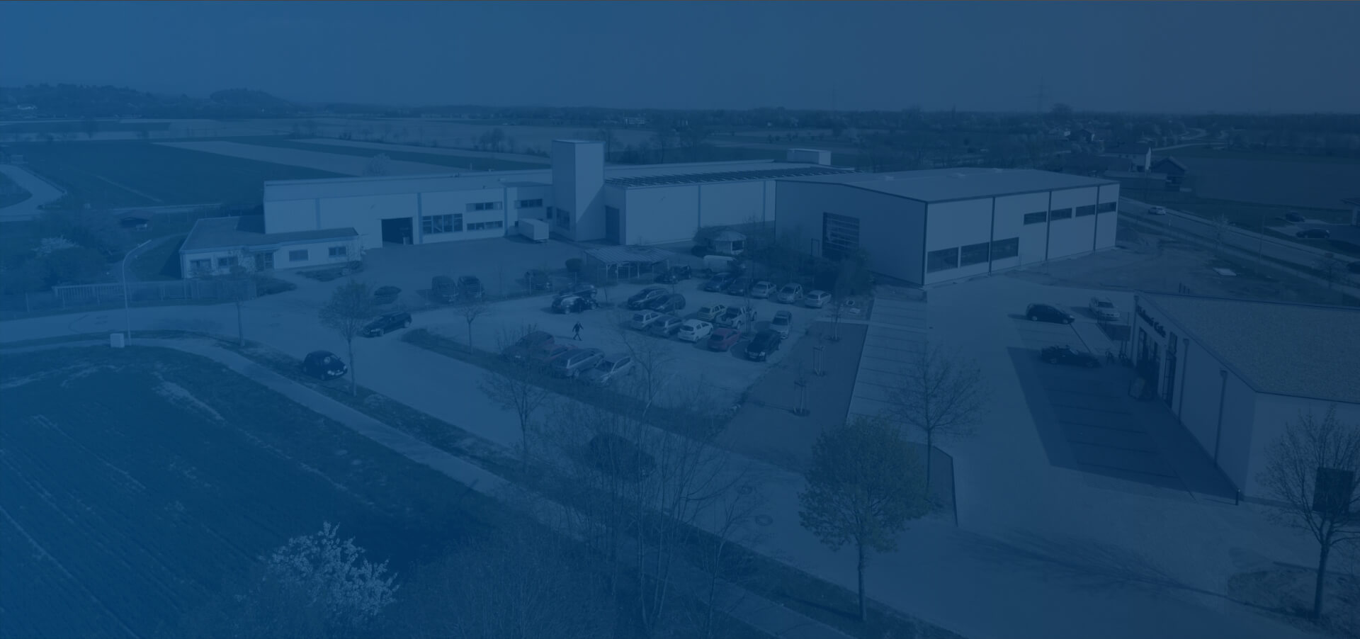 Firmengebäude Vogelperspektive mit blauem Farbverlauf